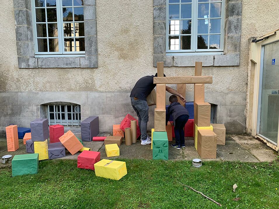 photo d'un enfant et d'un adulte en train de créer un château avec des boites en carton de couleurs