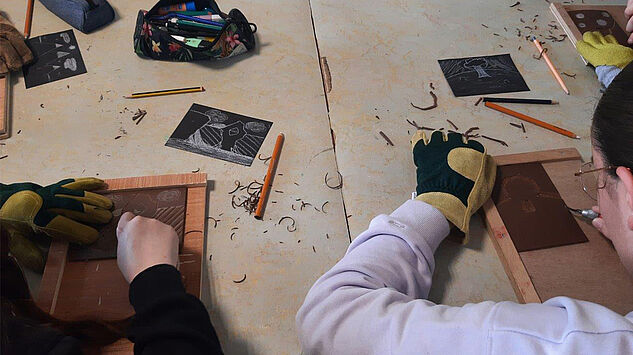 Atelier artistique avec des mains entrain de graver sur du linoleum