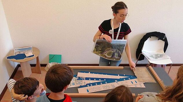 Médiatrice présentant la maquette du château à des enfants 