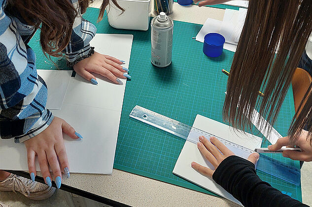 Fille qui coupe une feuille blanche avec un cutter