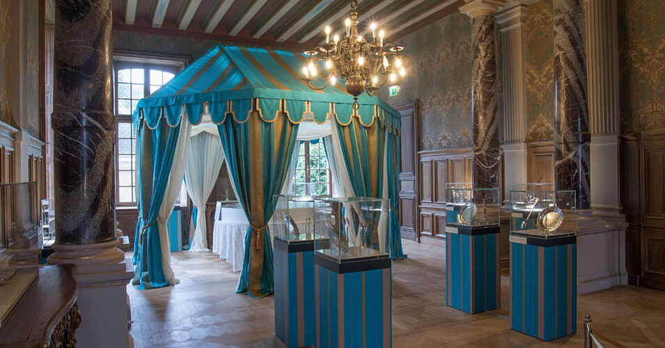 photo de la pièce accueillant l'exposition orfèvrerie civile du 18e siècle. Au centre, une tente or et bleue avec une table dressée en dessous